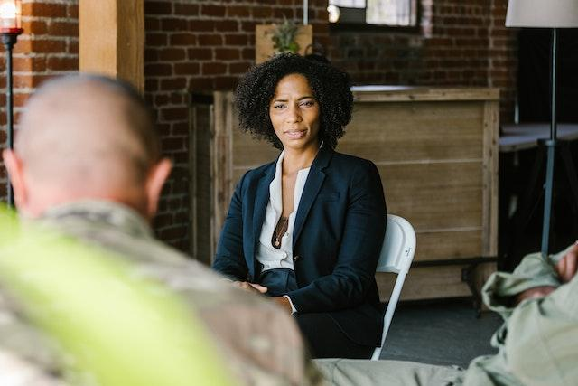 a focused woman discussing the benefits of peer support groups in addiction treatment with veterans
